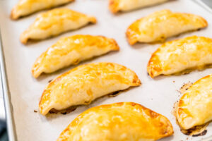 Frisch gebackene Puten-Empanadas mit goldbraunem Rand auf dem Backblech