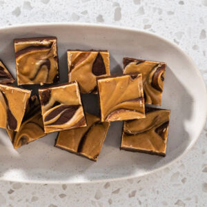 Marmorierte Fudge-Würfel mit Erdnussbutter-Swirl auf einem ovalen hellen Teller von oben