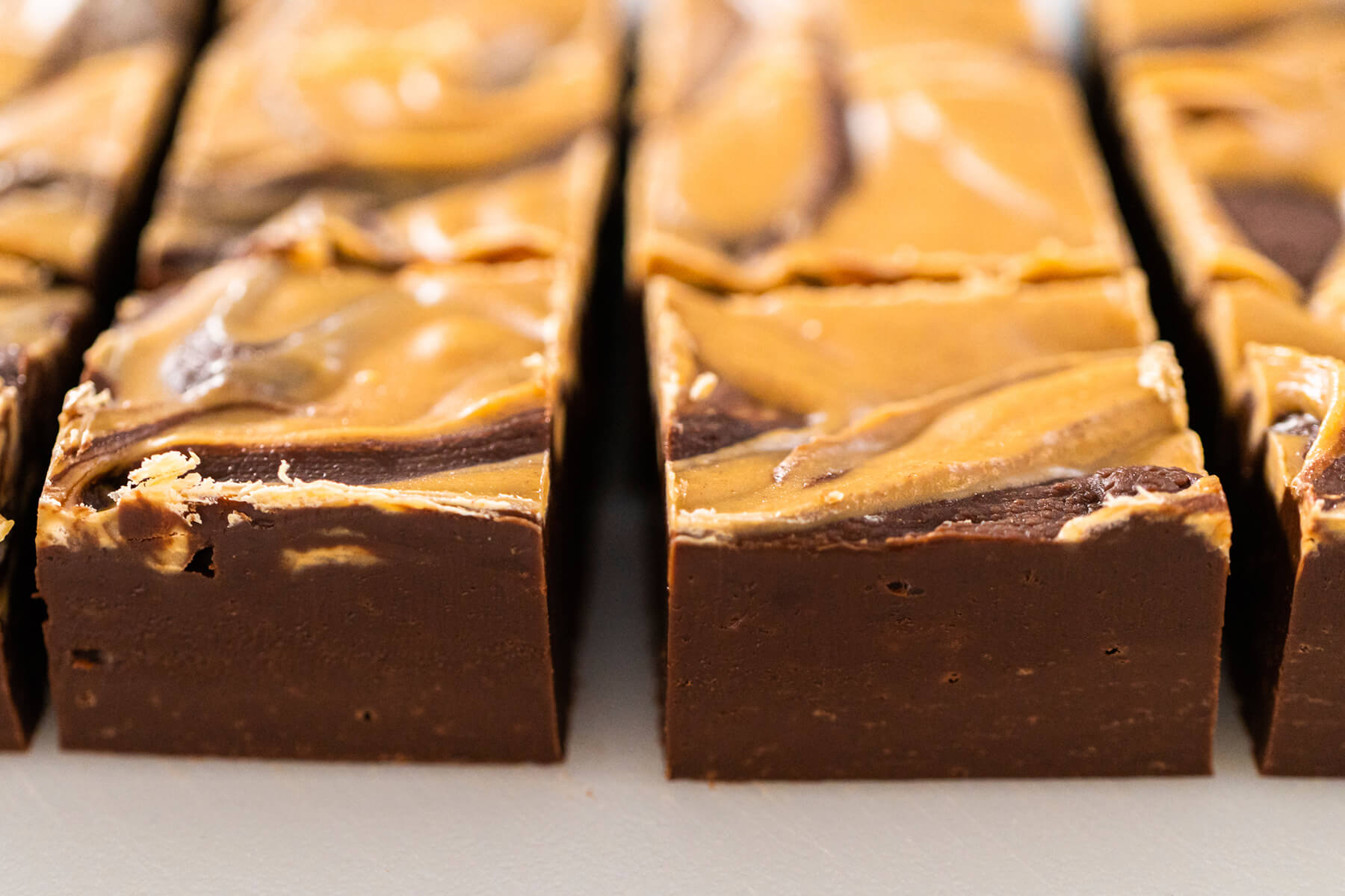 Reihe geschnittener Fudge-Würfel im Anschnitt mit dunkler Basis und heller Swirl-Decke