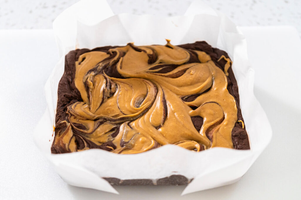 Marmorierter Fudge im mit Backpapier ausgelegten Rahmen kurz vor dem Kühlen