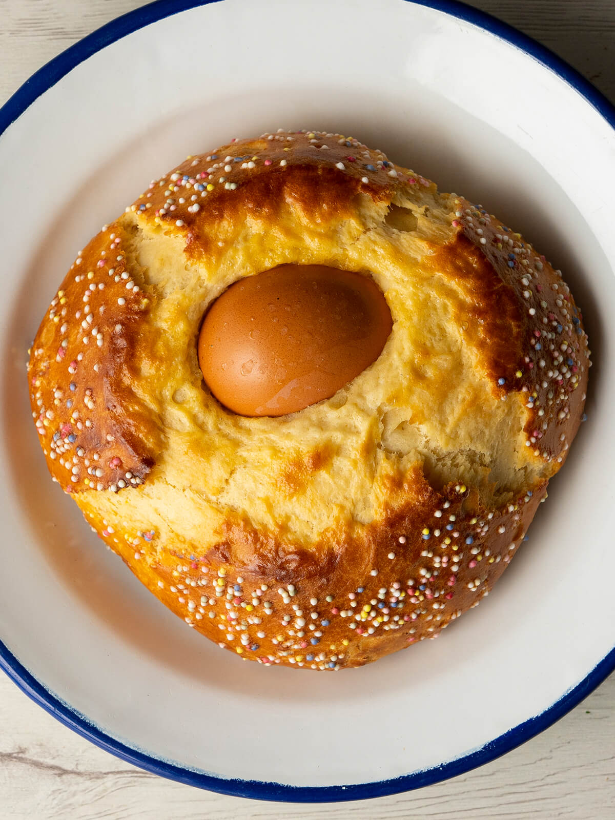 Spanisches Osterbrot Mona de Pascua von oben mit braunem Ei in der Mitte und bunten Zuckerperlen