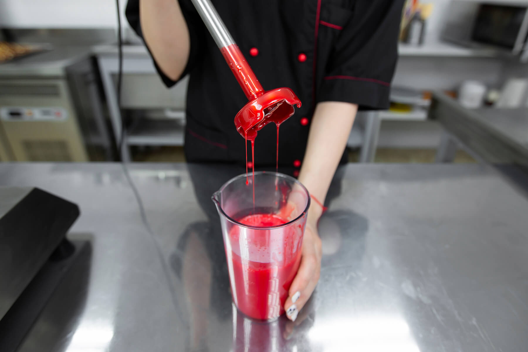 Fertig emulgierte rote Spiegelglasur läuft glänzend vom Stabmixer in den Becher zurück
