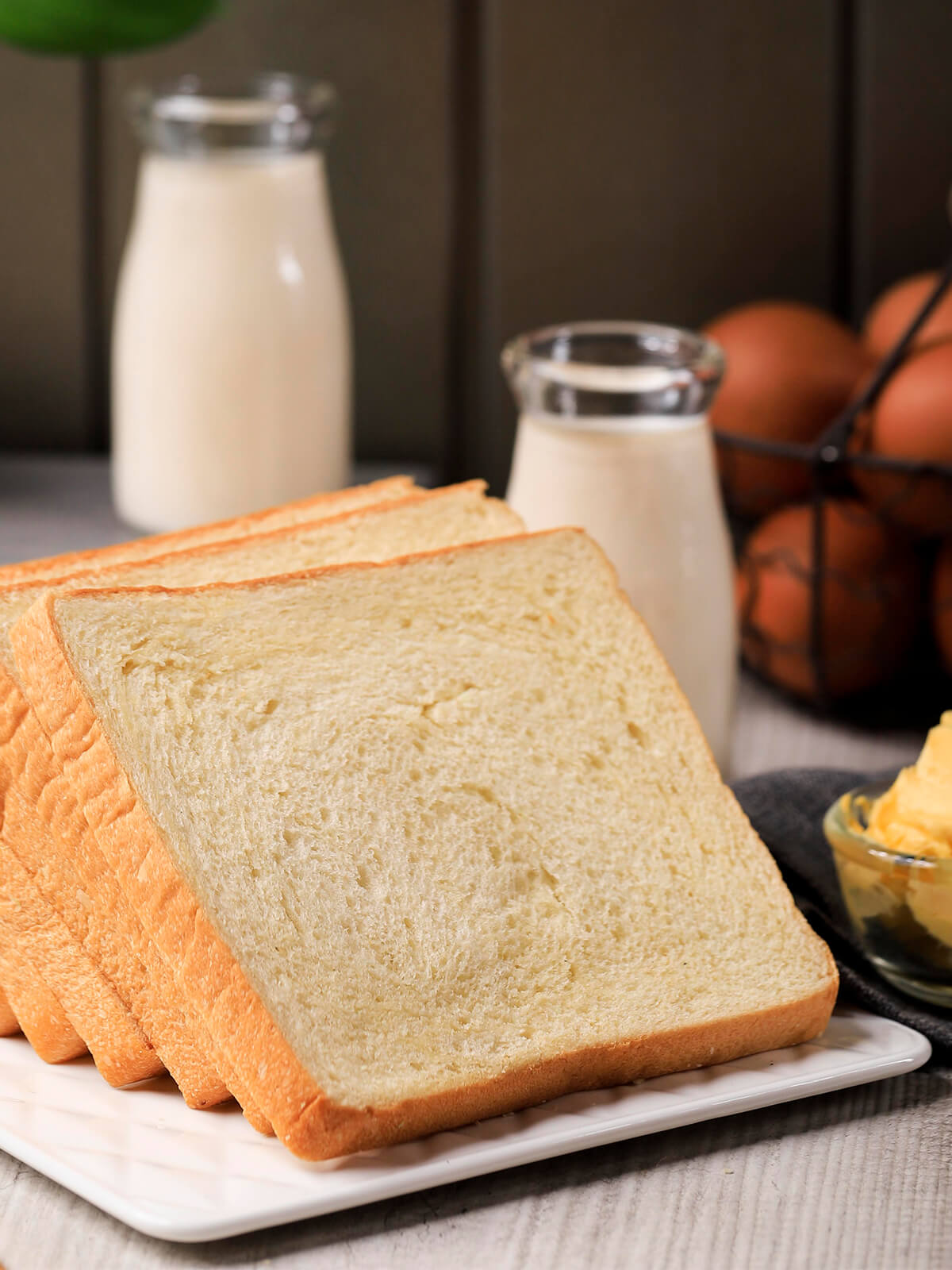 Dicke Scheiben helles Toastbrot mit cremefarbener feinporiger Krume und dünner goldener Kruste auf einer weißen Platte