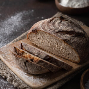 Angeschnittenes Vollkorn-Kartoffelbrot auf einem bemehlten Holzbrett mit heller feinporiger Krume