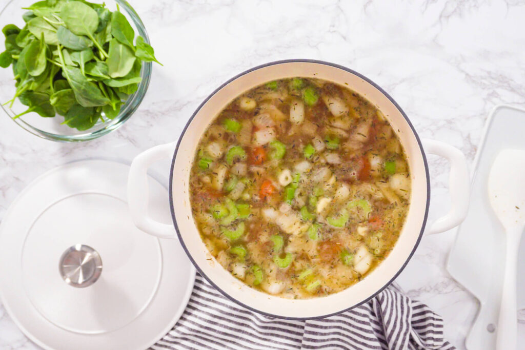Weiße Bohnensuppe mit Karotten, Sellerie und getrockneten Kräutern köchelt offen im Topf