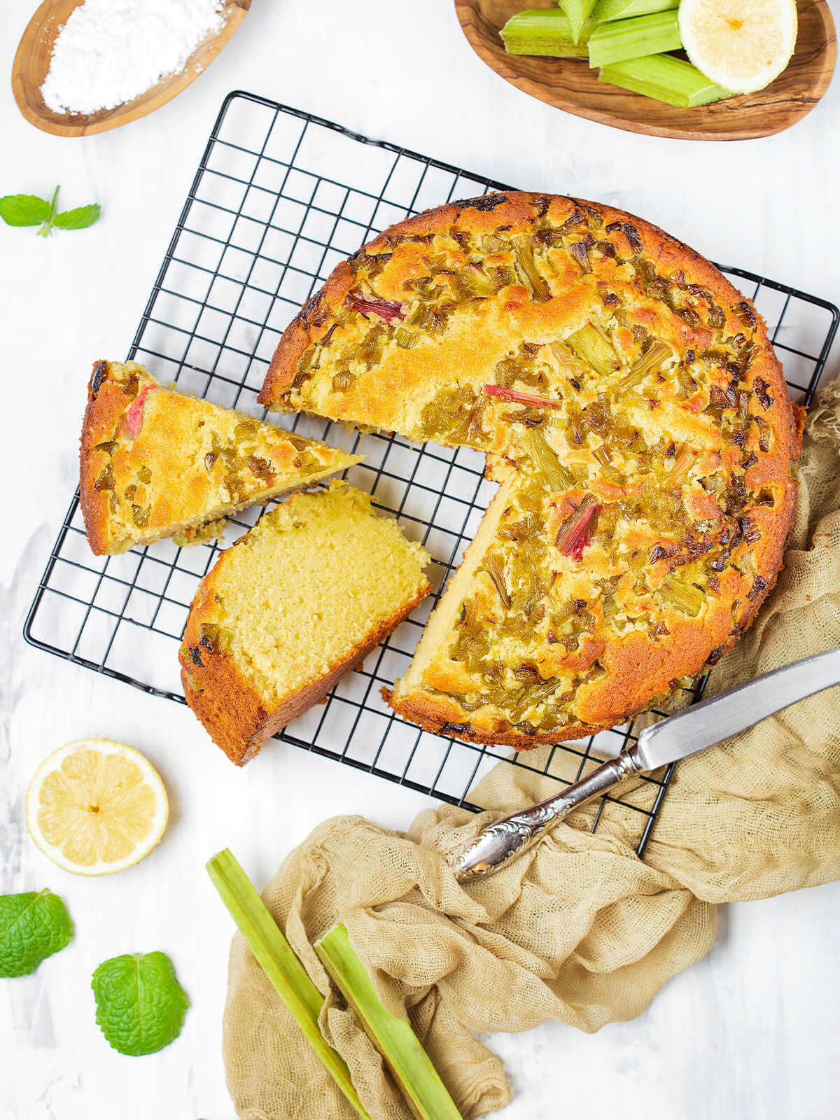 Runder Zitronenkuchen mit Rhabarber von oben, dicht belegt und mit Puderzucker bestäubt