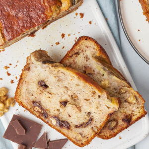 Zwei Scheiben Bananenbrot mit Walnussstücken und dunklen Schokoladenadern in der hellen Krume