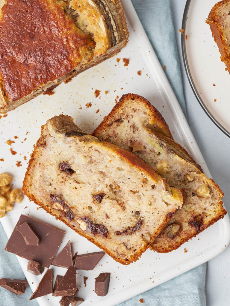 Zwei Scheiben Bananenbrot mit Walnussstücken und dunklen Schokoladenadern in der hellen Krume