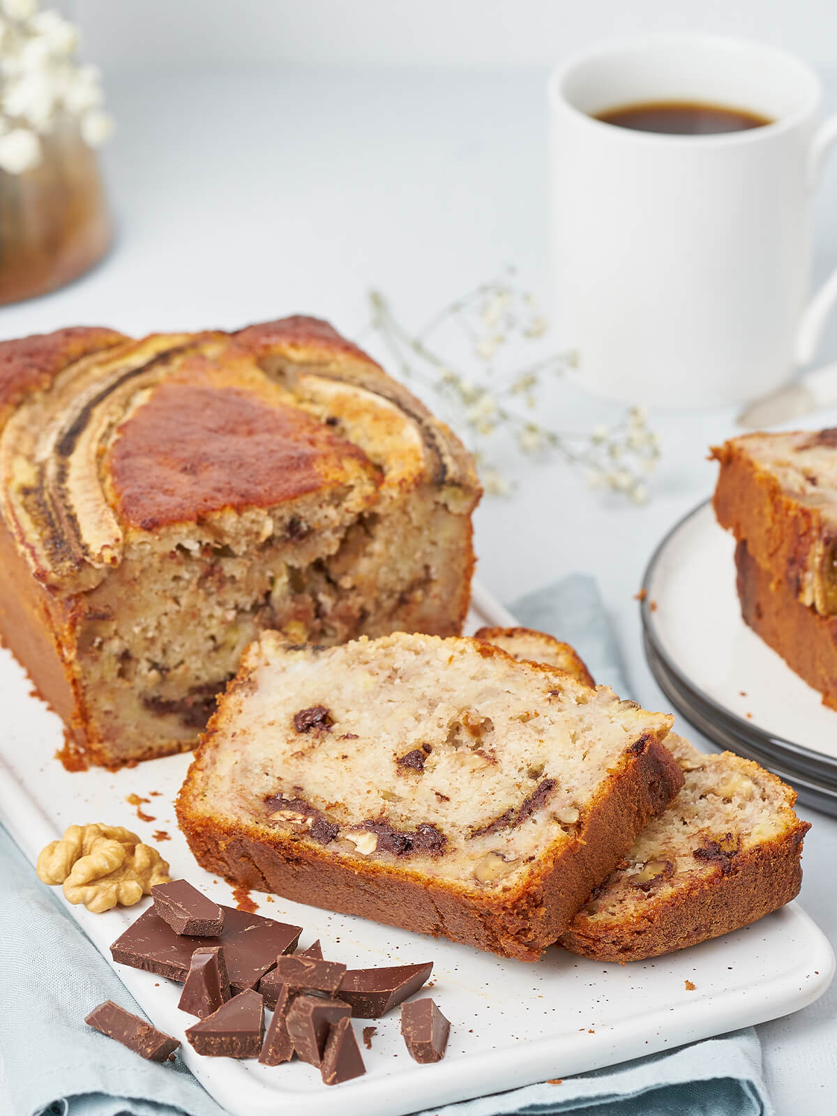 Scheibe Bananenbrot mit langen dunklen Schokoladenadern und hellen Walnussstücken in der Krume