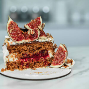 Angeschnittenes Stück einer Bento-Torte mit Möhrenboden, Frischkäsecreme, Cranberry-Füllung, Feigen und Walnüssen
