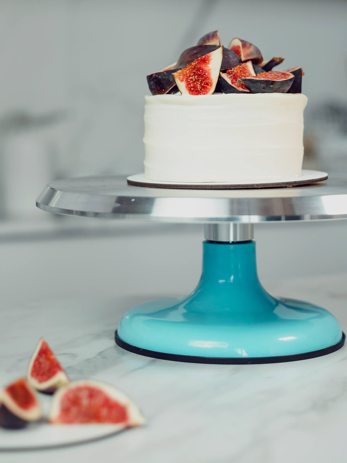 Kleine Bento-Torte mit weißer Frischkäsecreme und frischen Feigenvierteln auf einem Tortenständer