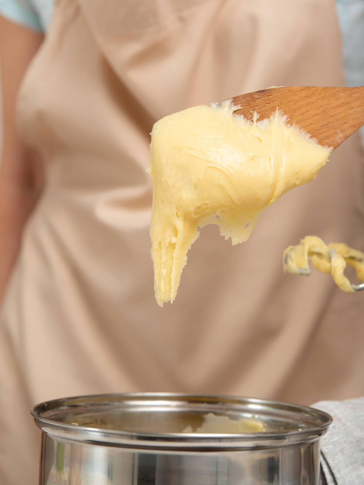 Zäher heller Teig hängt in einem spitzen Zipfel vom Holzlöffel und reißt nicht ab