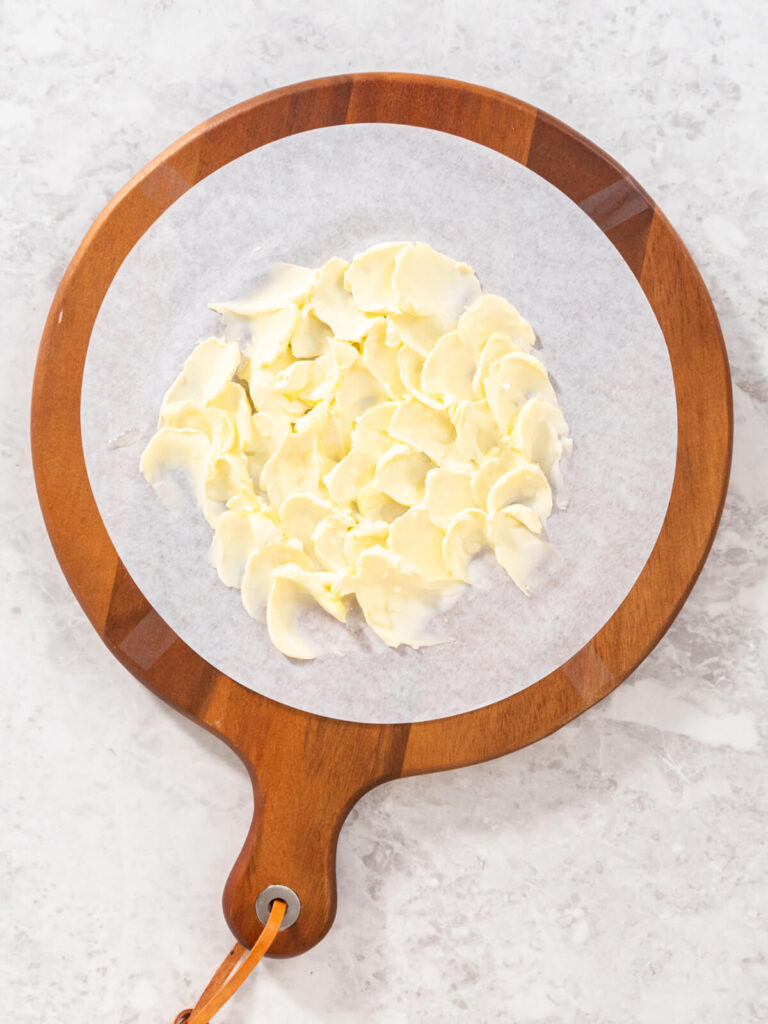 Weiche Butter in dekorativen Wellen auf Backpapier auf einem runden Holzbrett verstrichen