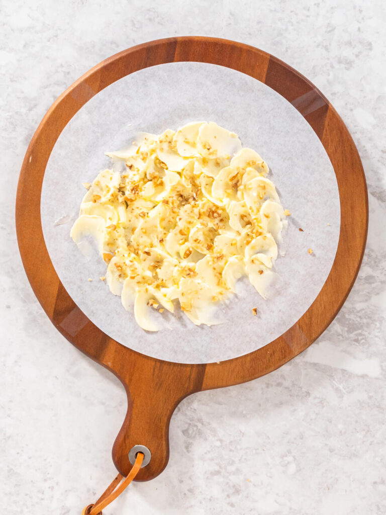 In Wellen gestrichene Butter, mit Olivenöl beträufelt und mit gerösteten Walnüssen bestreut