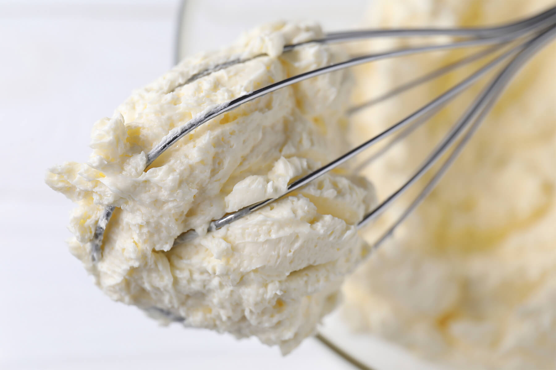 Nahaufnahme einer dichten Buttercreme mit feiner flockiger Struktur und einzelnen helleren gelben Butterstückchen