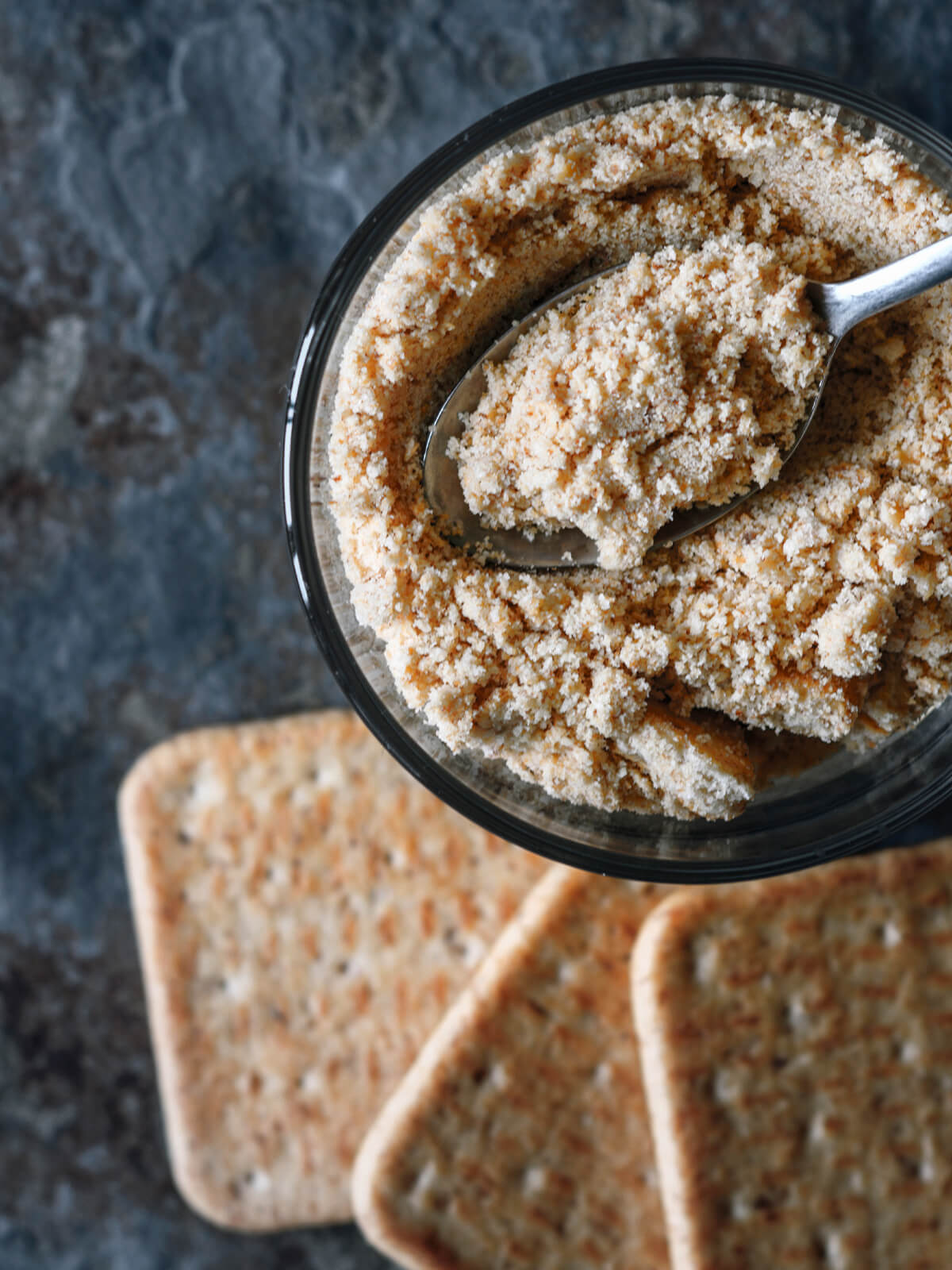 Zerdrückte Cracker in einer Glastasse von oben, daneben drei ganze Cracker