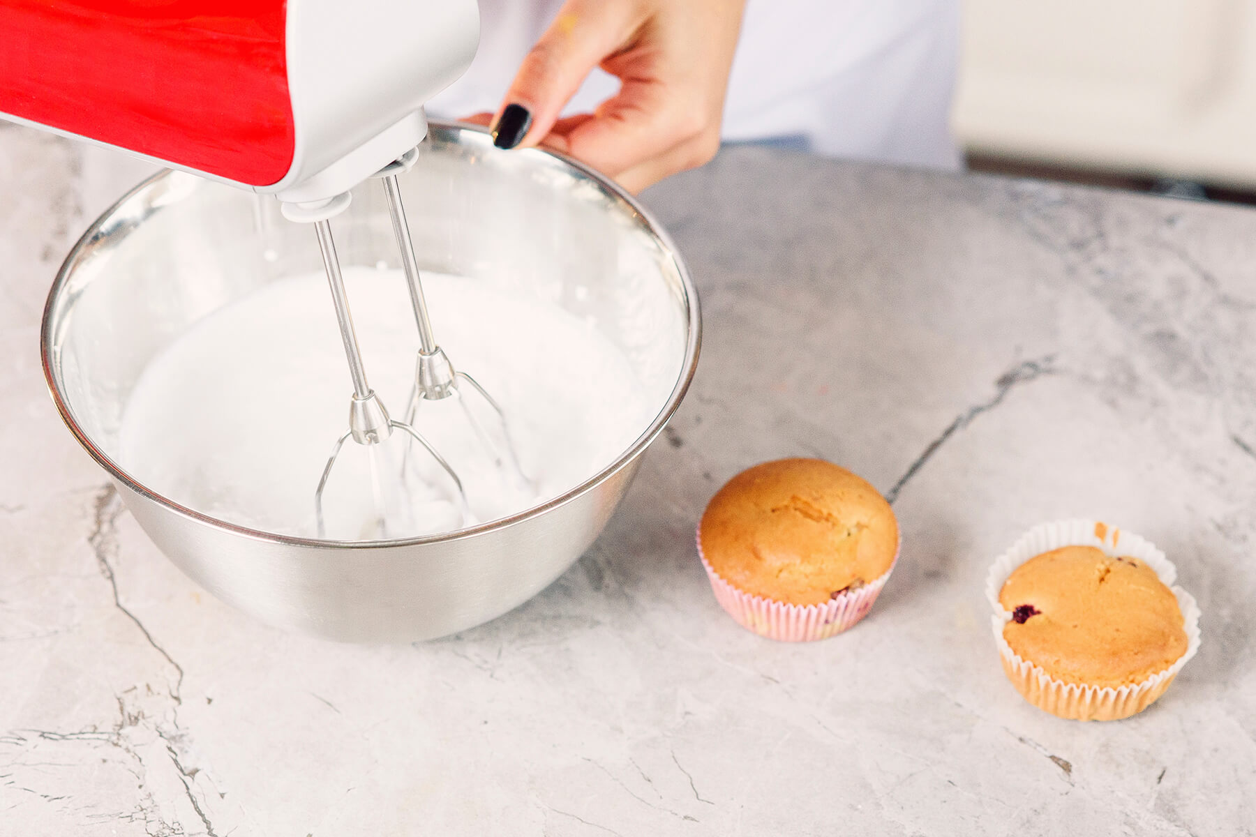 Weiße Crememasse im Handmixer, die Oberfläche noch glatt und ohne stehende Rillen