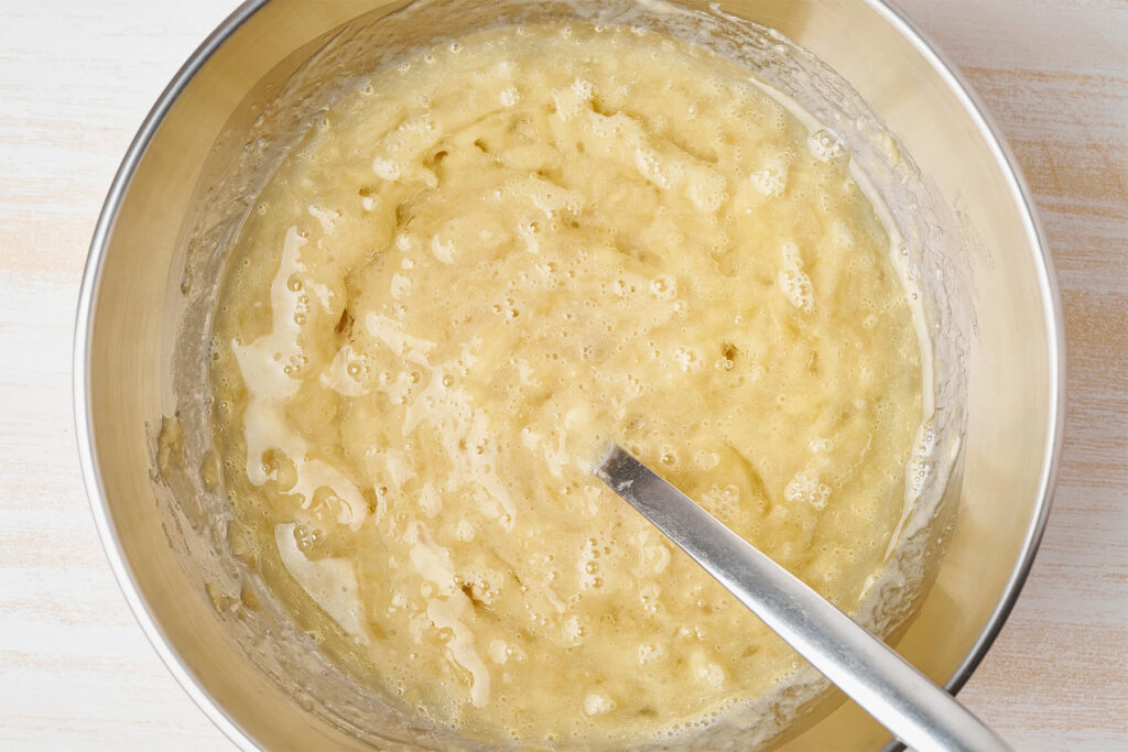Helle, schaumige Masse aus Bananenmus, Eiern, Zucker und Öl in der Rührschüssel