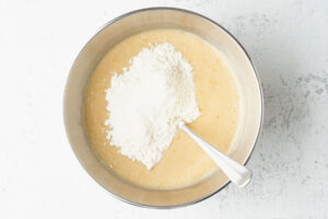 Die erste Portion Mehl liegt als Hügel auf der hellen Bananen-Joghurt-Masse