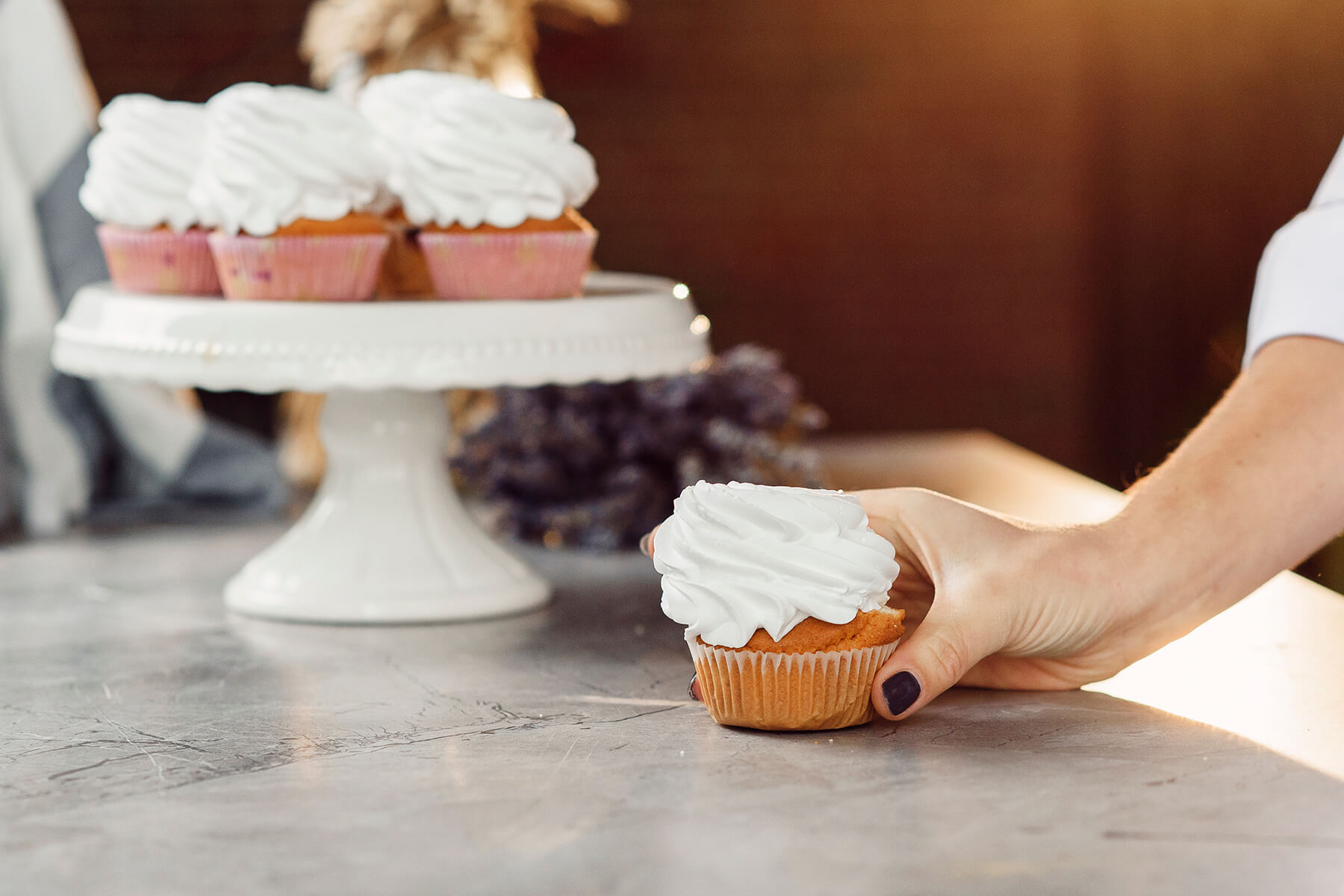 Eine Hand hält einen Cupcake mit einer flach gewordenen weißen Cremehaube