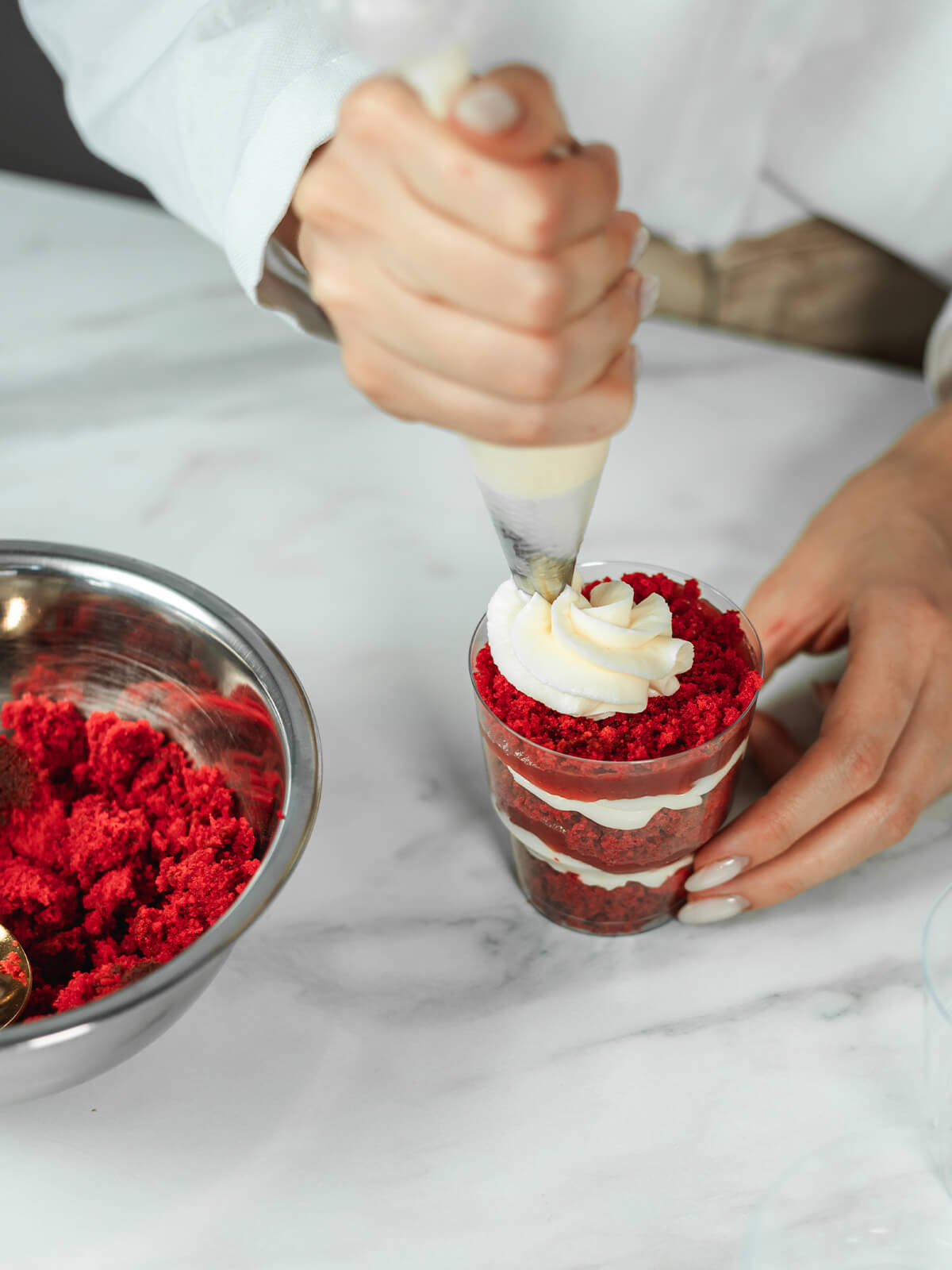 Frischkäsecreme wird mit einer breiten Tülle als Krone auf ein Dessertglas gespritzt