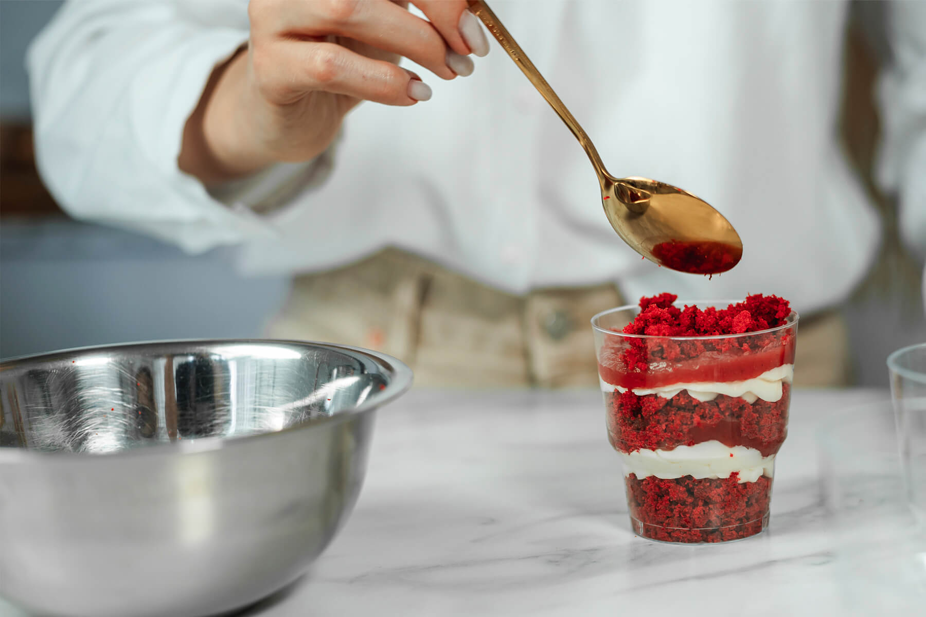 Fruchtpüree wird mit einem Löffel auf die oberste Schicht eines Schichtdesserts im Glas gegeben
