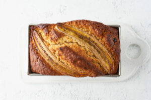 Fertig gebackenes Bananenbrot mit Heidelbeeren in der Kastenform mit karamellisierten Bananenhälften