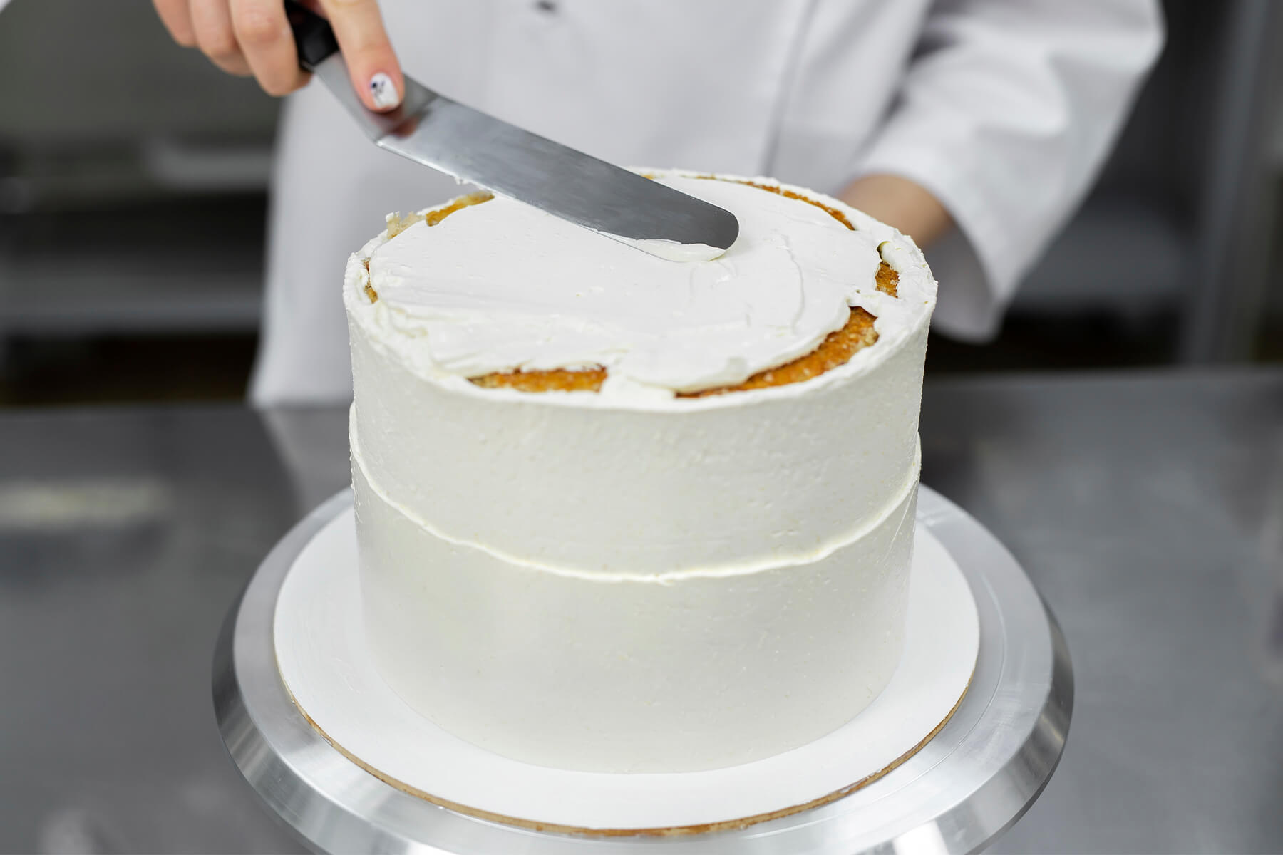 Lange gerade Palette mit stumpfer Kante verteilt Creme flach über die Oberseite einer Torte