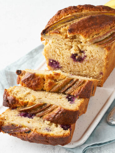 Aufgeschnittenes Bananenbrot mit Heidelbeeren, drei Scheiben liegen vor dem Laib