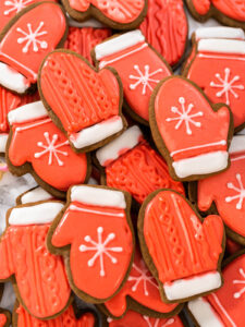 Fertig verzierte Lebkuchen-Fäustlinge mit roter Fläche, weißer Manschette, weißer Schneeflocke und rotem Strickmuster