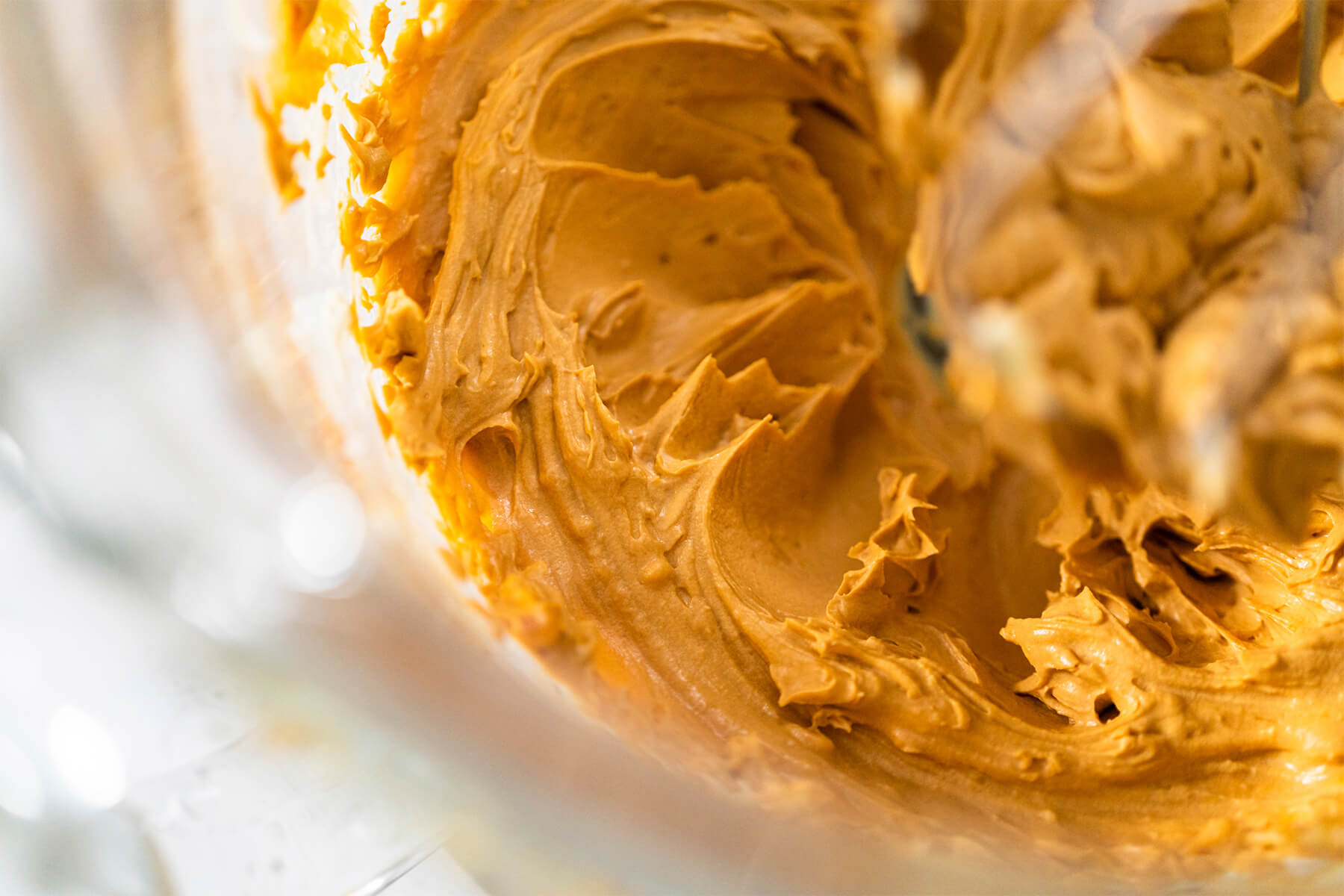 Nahaufnahme der glatt aufgeschlagenen karamellfarbenen Buttercreme in der Rührschüssel