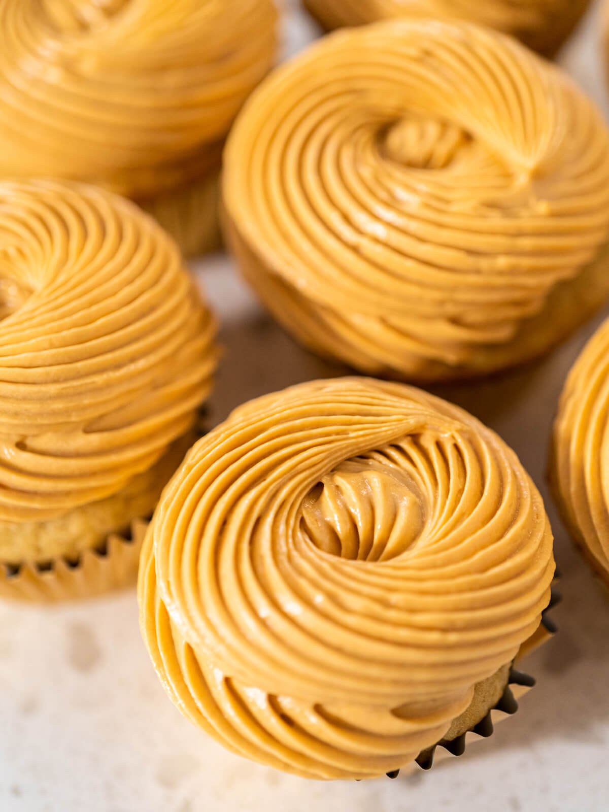 Nahaufnahme der spiralförmig aufgespritzten Dulce-de-Leche-Buttercreme auf den Cupcakes