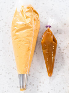 Zwei Spritzbeutel nebeneinander: Dulce-de-Leche-Buttercreme mit Sterntülle und dickflüssige Karamellsauce