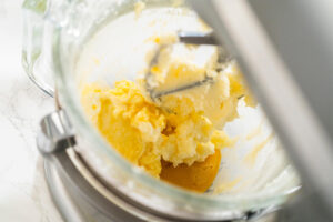 Hell aufgeschlagene Butter-Zucker-Masse mit einem Ei in der Glasschüssel der Küchenmaschine