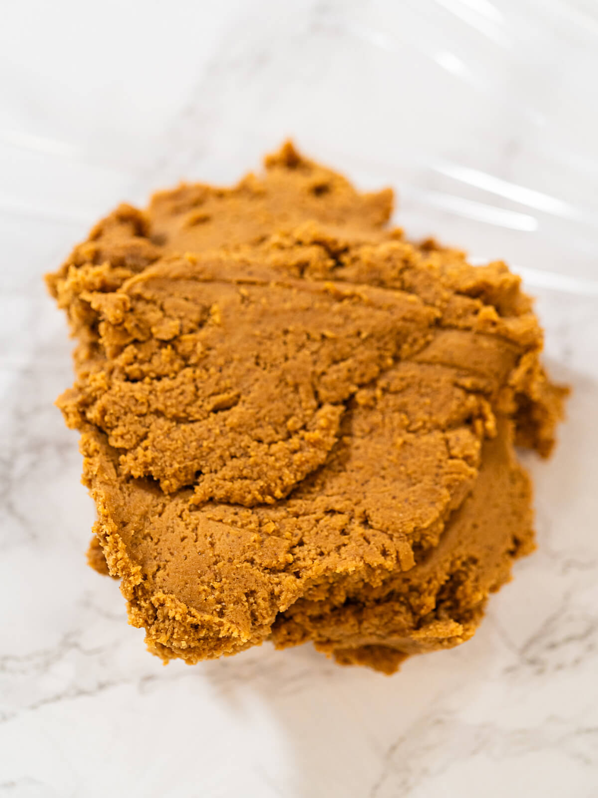 Frisch gekneteter, warm brauner Lebkuchenteig auf einem Bogen Frischhaltefolie