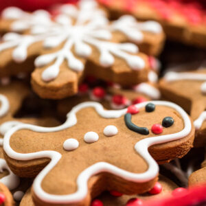 Klassischer Lebkuchen-Mann mit weißer Konturglasur neben einer verzierten Schneeflocke und roten Zuckerperlen