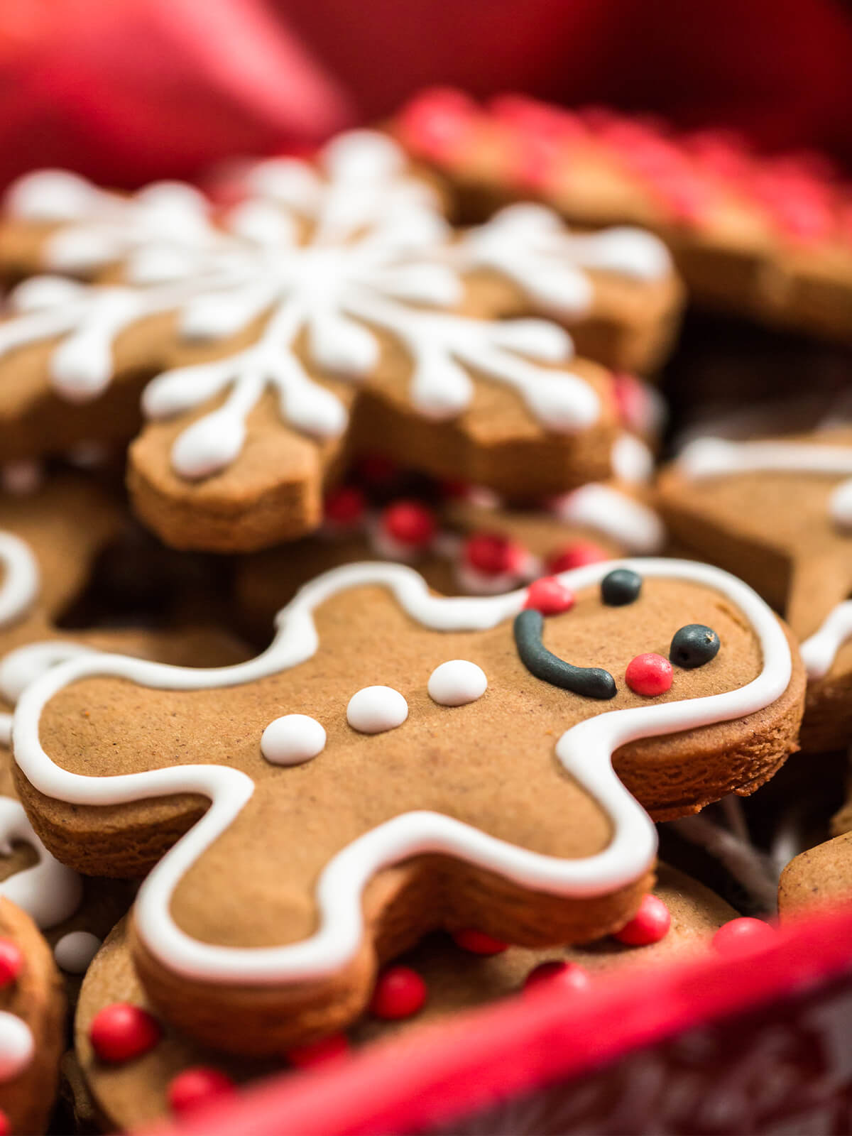 Klassischer Lebkuchen-Mann mit weißer Konturglasur neben einer verzierten Schneeflocke und roten Zuckerperlen