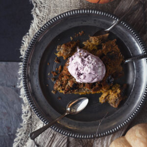 Portion Kürbis-Dump-Cake von oben auf einem Zinnteller, krümelige goldbraune Kruste mit dunklen Karamellstellen und eine Kugel Beereneis