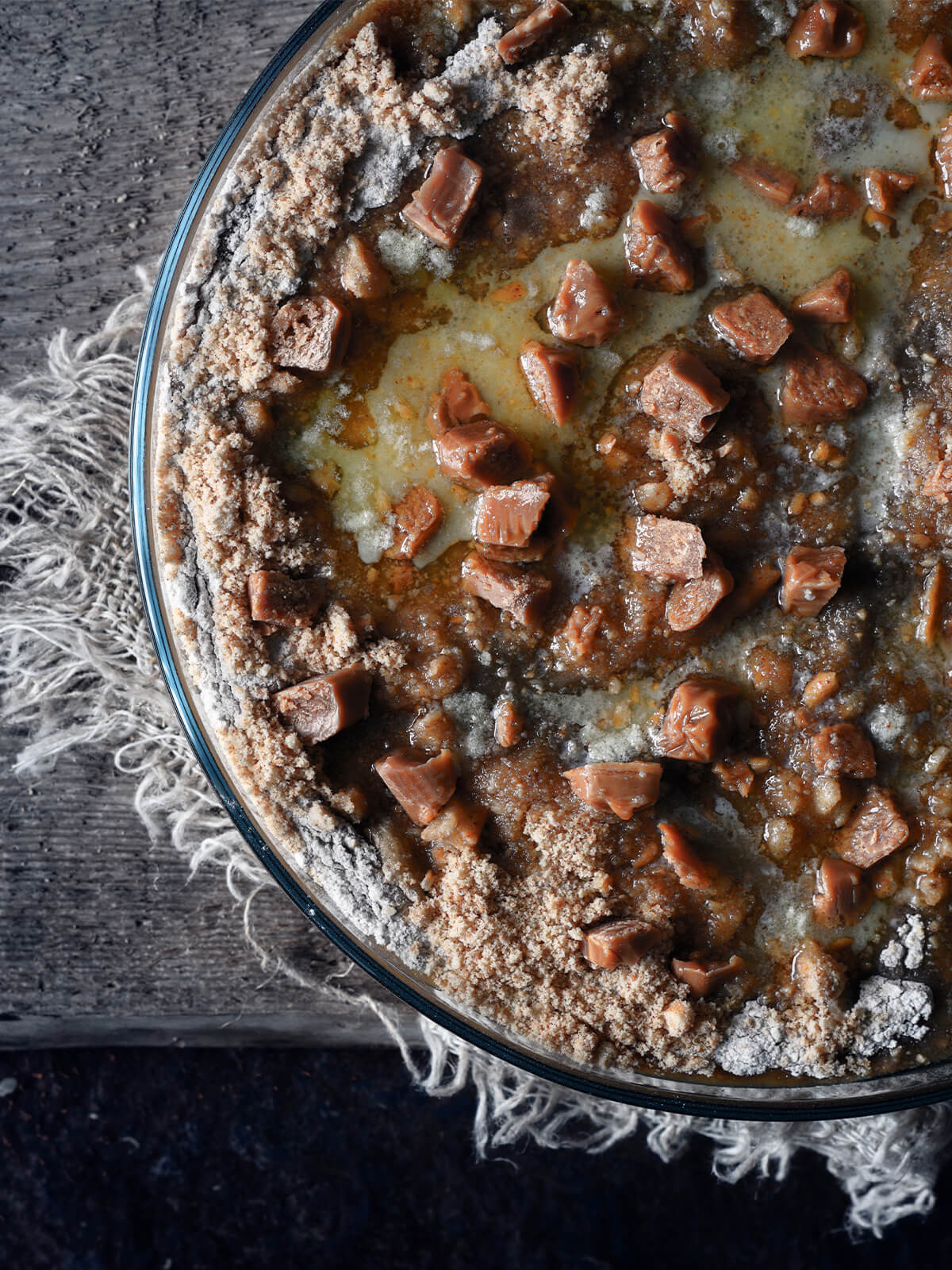 Ungebackener Kürbis-Dump-Cake von oben, in der Mitte eine glänzende Butterpfütze, am Rand noch helle, trockene Mehlstellen