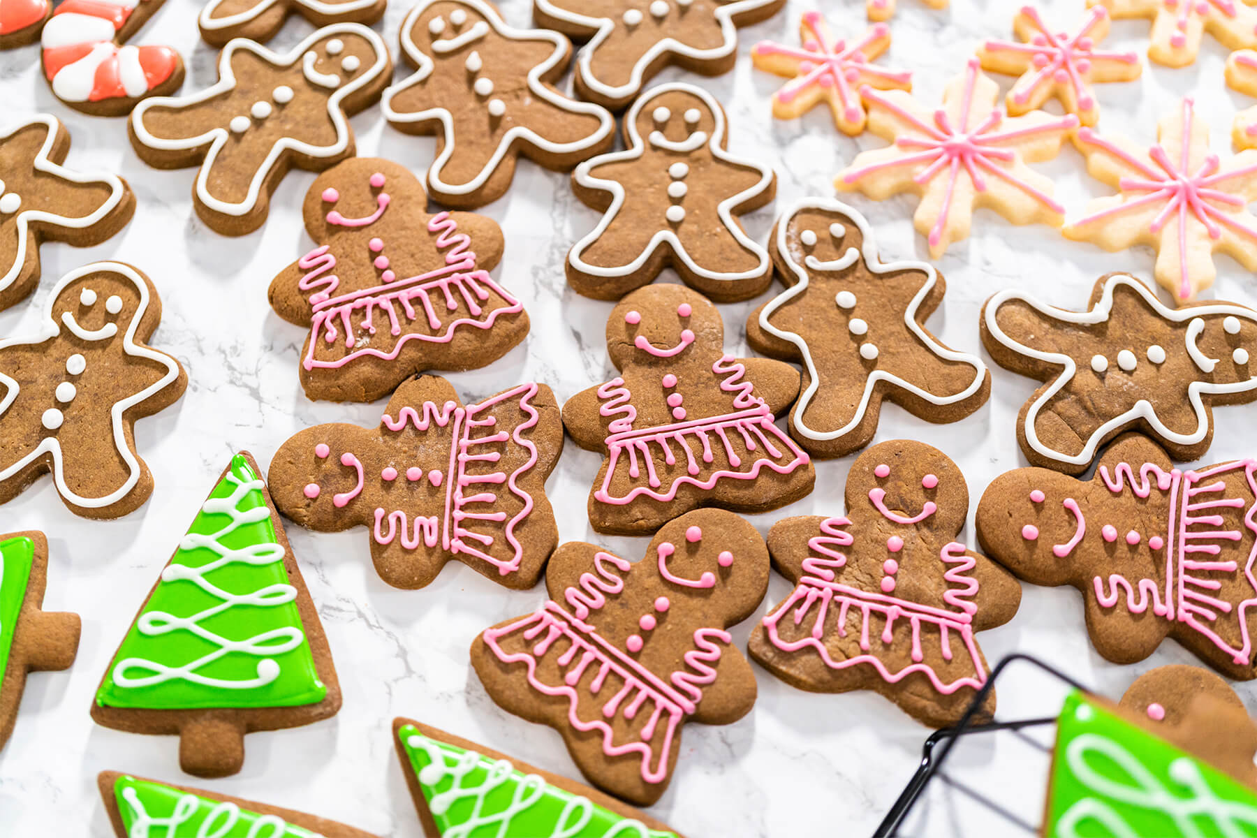 Verzierte Lebkuchen in Weiß, Rosa und Grün neben helleren Schneeflocken-Keksen mit rosa Linien