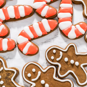Fertig verzierte Lebkuchen-Zuckerstangen mit rot-weißen Streifen neben weiß umrandeten Lebkuchen-Männchen