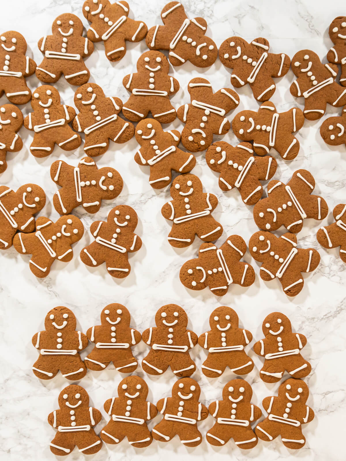 Viele weiß verzierte Lebkuchen-Männchen von oben auf einer Marmorfläche ausgelegt