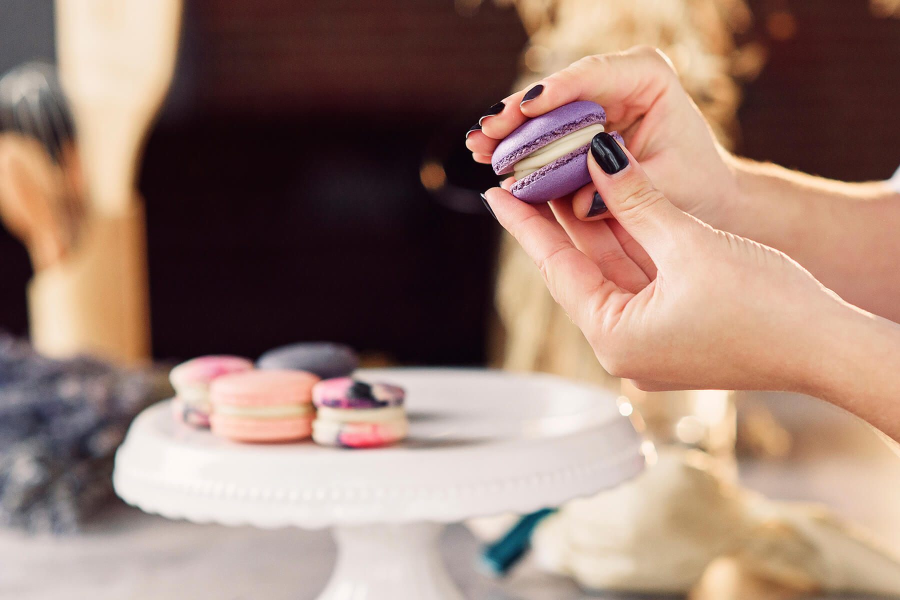 Zwei violette Macaronhälften werden mit einer weißen Cremeschicht dazwischen zusammengedrückt