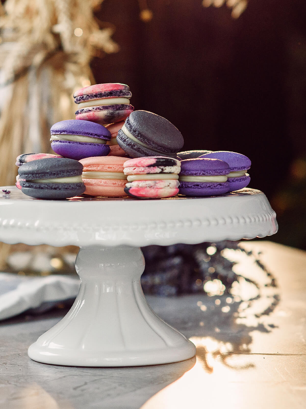 Mehrere gefüllte Macarons im Profil auf einer weißen Tortenplatte, unter jeder glatten Haube die raue Fußkrause