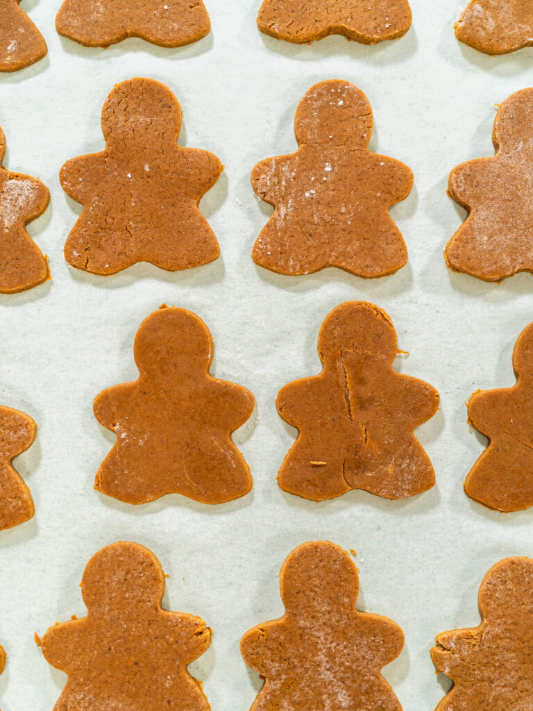 Ausgestochene rohe Lebkuchen-Figuren mit sauberen Kanten auf einem Bogen Backpapier