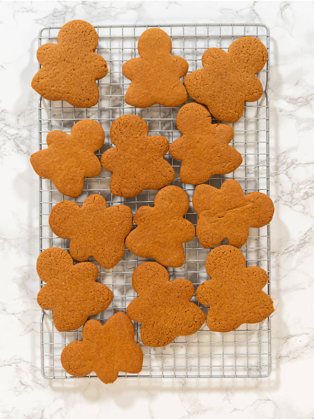 Gebackene Lebkuchen-Figuren auf einem Abkühlgitter über heller Marmorfläche