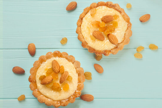 Zwei feine Mandel-Tartelettes aus mürbem Sandteig mit Creme, Mandeln und Rosinen