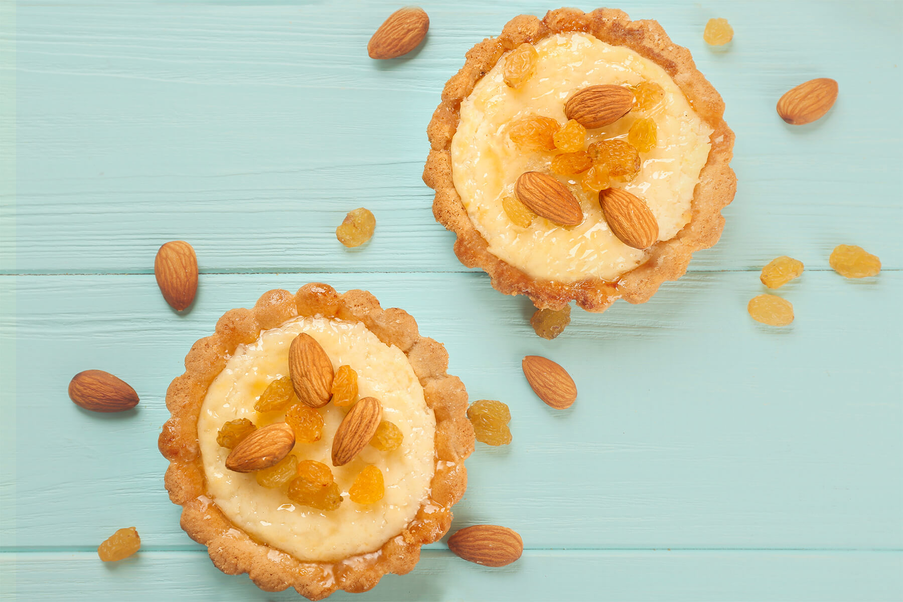 Zwei feine Mandel-Tartelettes aus mürbem Sandteig mit Creme, Mandeln und Rosinen