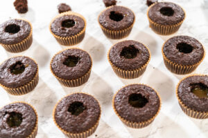 Zwölf Schokoladen-Cupcakes, deren Mulden mit hell goldenem, glänzendem Karamell gefüllt sind