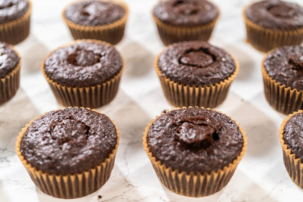 Gefüllte Schokoladen-Cupcakes, bei denen die ausgestochenen Teigstücke als Deckelchen wieder auf die Mulden gesetzt sind